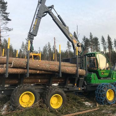Stor maskin arbeider med trestammer i skogen